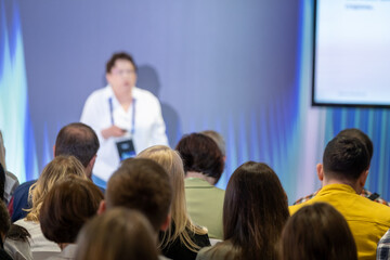 Group of people attentively listening to a speaker during a business conference event, with a focus on teamwork, learning, and communication.