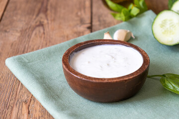 White dip sauce - sour cream or yogurt in wooden bowl. Greek sauce 
