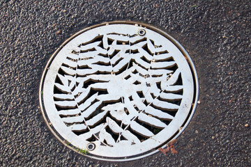 beautiful iron white round hatch in the asphalt