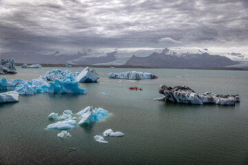 Group of athletes kayaking around melting icebergs in iceland