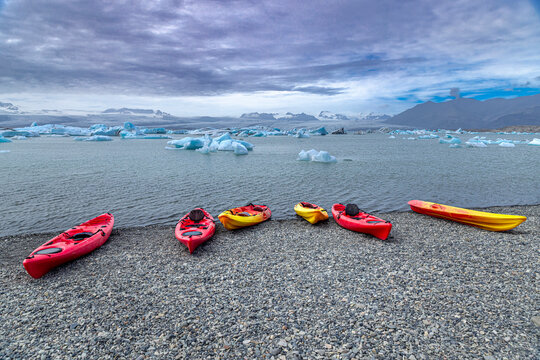 Colorful kayaks resting on a rocky beach awaiting kayakers in iceland