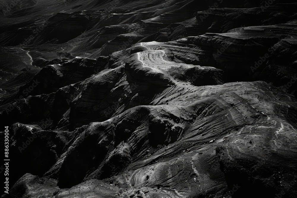 Poster a black and white view of a rugged mountain range under deep shadows, deep, inky shadows cast across