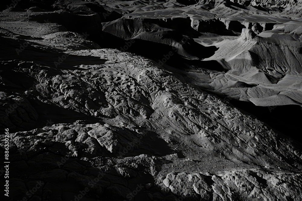 Poster black and white canyon landscape with shadows on bumpy terrain, deep, inky shadows cast across a bum
