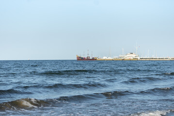 Photo of the sea and a pier in the distance. A pirate ship in the distance.