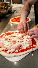 pizza maker hands pour ingredients into a pizza dough