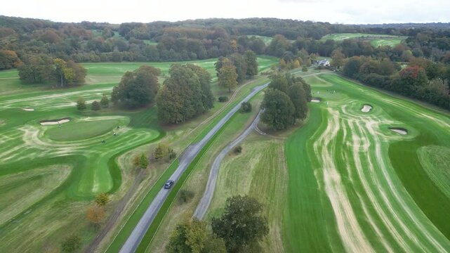 golf course county club large high end luxury resort driving through car. A view from a height of people playing golf. Active pastime in the fresh air