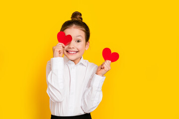 Photo of cute schoolgirl hold cover eye small heart empty space wear uniform isolated on yellow color background