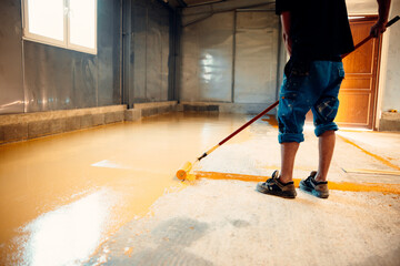 Fototapeta premium Construction worker applying epoxy resin coating on concrete floor using a roller