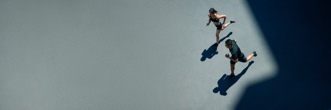 Banner. Aerial view of young people jogging together outdoor on sunny summer day at park. Negative space to insert your text. Concept of sport and healthy lifestyle, pair training, leisure activity.