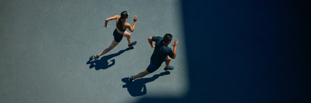 Banner. Aerial view of young people jogging together outdoor on sunny summer day at park. Negative space to insert your text. Concept of sport and healthy lifestyle, pair training, leisure activity.