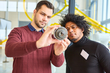Engineers inspecting a mechanical component for robotics and automation development