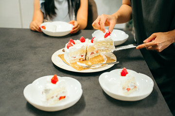 ショートケーキを切り分けるお母さんと待つ子供