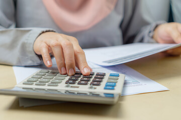 Close up of muslim woman planning home budget and using calculator