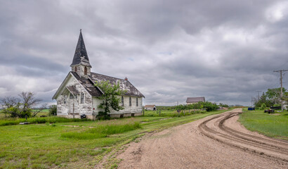 Old abandoned wooden church beside a gravel street in the village of Wartime, Saskatchewan, Canada