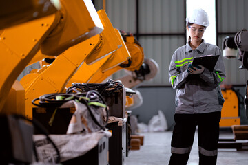 Fototapeta premium Industrial engineer working on robot maintenance in AI futuristic electronic technology factory. Female technician checking automated robotic machine. Modern smart woman empowerment in industry 4.0.