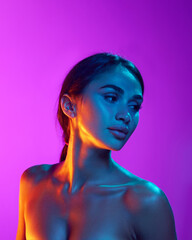 Spa care and wellness. Portrait of attractive young woman with perfect tanned body, spotless skin and glossy black hair against purple background in neon. Beauty, skincare, cosmetology, cosmetics