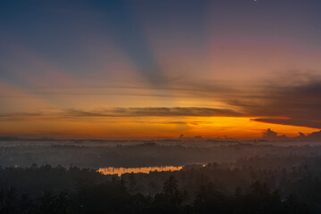The sun is setting over a foggy valley in Sri Lanka, casting a warm glow over the mist-covered landscape.