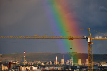 rainbow over the construction site with a crane and city industrial zone 