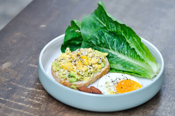 bread with egg and avocado topping with sunny side up egg , lettuce and almond