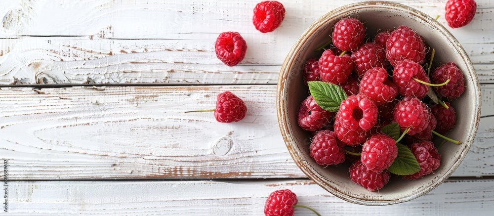 Aufkleber red ripe raspberries with stems in a bowl on a white rustic wooden surface. top view of organic berr