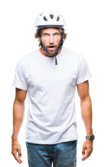 Handsome hispanic cyclist man wearing safety helmet over isolated background afraid and shocked with surprise expression, fear and excited face.