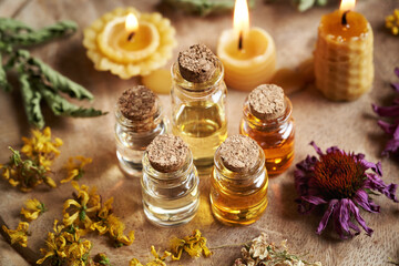 Bottles of aromatherapy essential oils with dry herbs and flowers and beeswax candles