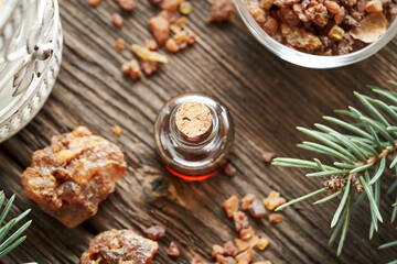 A bottle of myrrh essential oil and resin with spruce branches