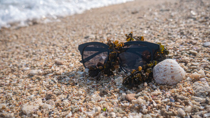 sunglasses with sea coral placed on white beach sand, tropical beach, summer on the beach, summer holiday accessories on the sandy beach