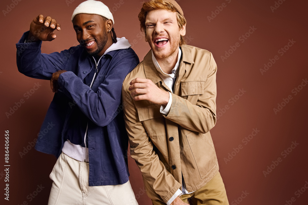 Wall mural Two stylish multicultural men pose in front of a brown background.