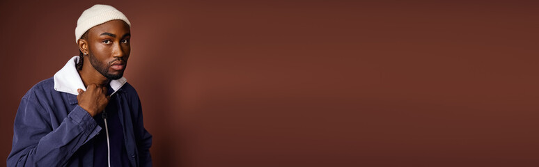 A stylish African American man wearing a blue jacket and a white hat.