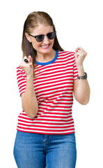 Middle age mature woman wearing sunglasses over isolated background very happy and excited doing winner gesture with arms raised, smiling and screaming for success. Celebration concept.