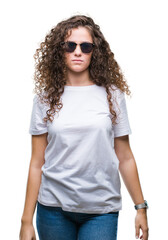 Beautiful brunette curly hair young girl wearing sunglasses over isolated background with serious expression on face. Simple and natural looking at the camera.