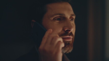 Smiling businessman speaking cellphone standing evening panoramic window closeup