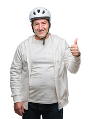 Handsome senior cyclist man wearing bike helmet over isolated background happy with big smile doing ok sign, thumb up with fingers, excellent sign