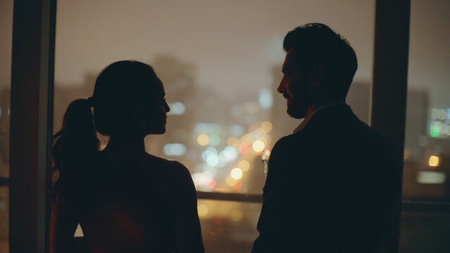 Romantic spouses silhouettes celebrating anniversary night city window closeup