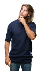 Young handsome man with long hair wearing winter sweater over isolated background with hand on chin...