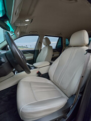 Car interior, white leather seats, central steering wheel, driver's and passenger's seats visible the luxurious setting highlights a modern and comfortable driving experience