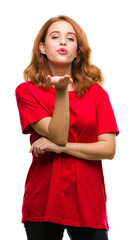 Young beautiful woman over isolated background looking at the camera blowing a kiss with hand on air being lovely and sexy. Love expression.