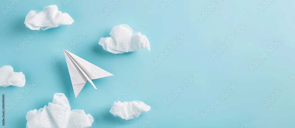 Aufkleber top view of white paper origami airplane on pastel blue background with clouds suitable for copy spa