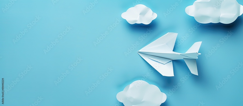 Aufkleber top view of white paper origami airplane on pastel blue background with clouds suitable for copy spa