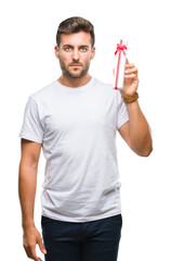 Young handsome man in love giving valentine present over isolated background with a confident...