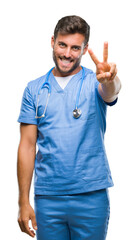 Young handsome doctor surgeon man over isolated background smiling looking to the camera showing fingers doing victory sign. Number two.