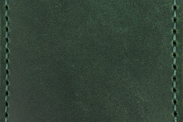 Fototapeta premium Green leather surface with stitching along the vertical edges and copyspace.
