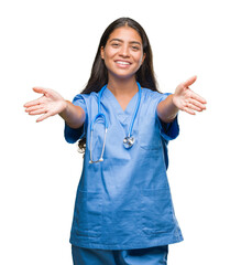 Young arab doctor surgeon woman over isolated background looking at the camera smiling with open arms for hug. Cheerful expression embracing happiness.