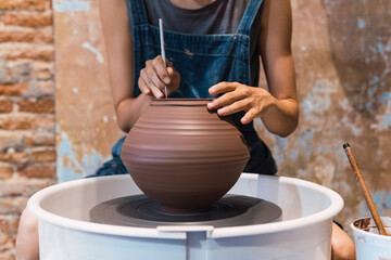 Close up of female hands of an artist making ceramic bowl on potters wheel