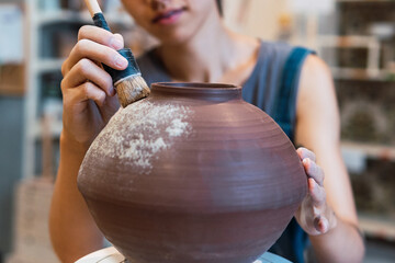 Creative young woman artist molding clay on pottery wheel, Workshop in ceramic studio, clay making of a ceramic pot on the pottery wheel, hobby and leisure with pleasure concept