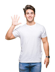 Naklejka premium Young handsome man wearing white t-shirt over isolated background showing and pointing up with fingers number five while smiling confident and happy.