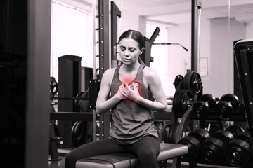 Heart attack. Young woman suffering from pain and pressing hands to chest at gym