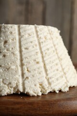 Tasty ricotta (cream cheese) on wooden table, closeup