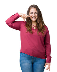 Beautiful plus size young woman over isolated background Pointing with hand finger to face and nose, smiling cheerful